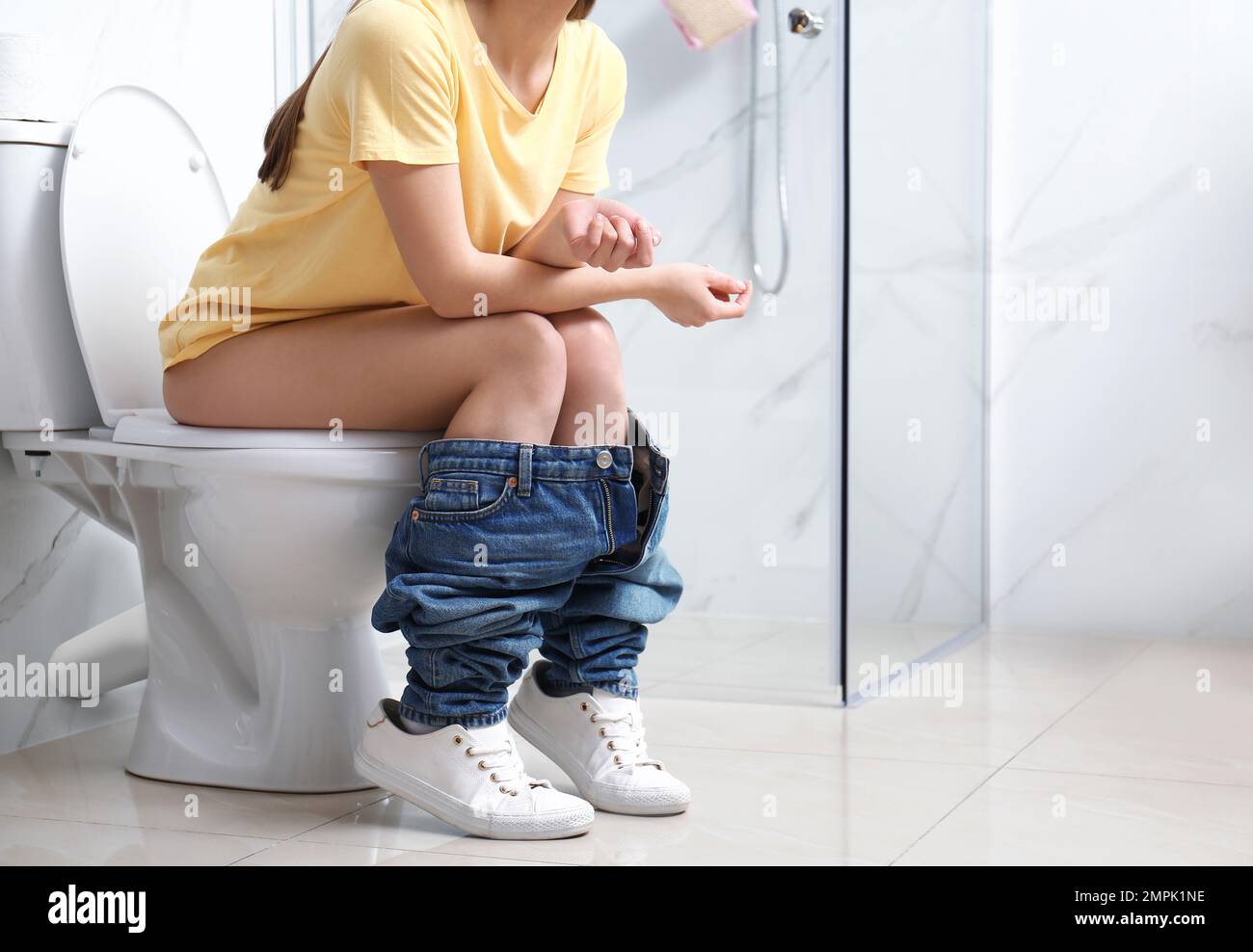 Woman sitting on toilet bowl in bathroom, closeup Stock Photo - Alamy, image size:1300x988