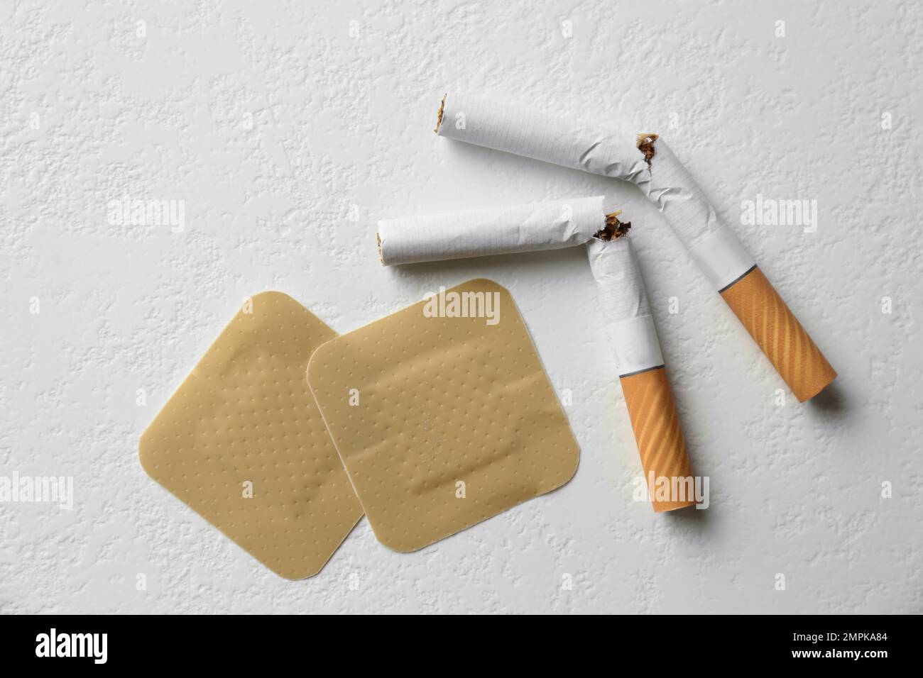 Nicotine patches and broken cigarettes on white background, flat lay