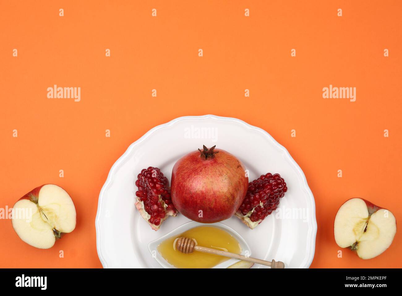 Honey, apples and pomegranate on orange background, flat lay. Rosh