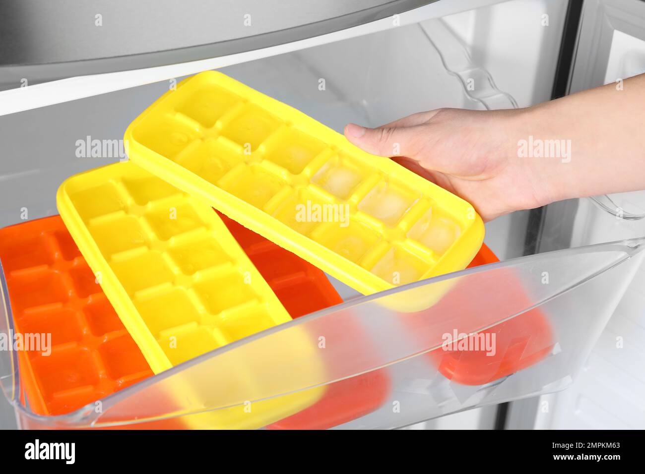https://c8.alamy.com/comp/2MPKM63/woman-taking-tray-with-ice-cubes-from-fridge-closeup-2MPKM63.jpg