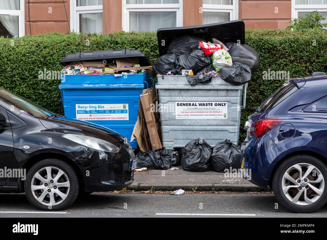 Overflowing domestic rubbish bin and black plastic bags on a pavement waiting to be cleared, Glasgow, Scotland, UK, Europe Stock Photo