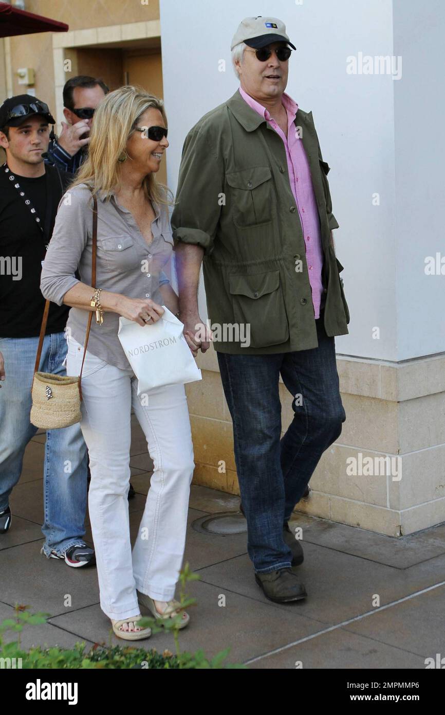 Veteran actor Chevy Chase holds hands with his wife Jayni Chase as they walk around The Grove shopping center where Chevy joined the American TV show 'Extra' for an interview.  Jayni, who has been married to Chevy for 28 years, looked very happy as she held a small Nordstrom bag. Los Angeles, CA. 10/07/10. Stock Photo