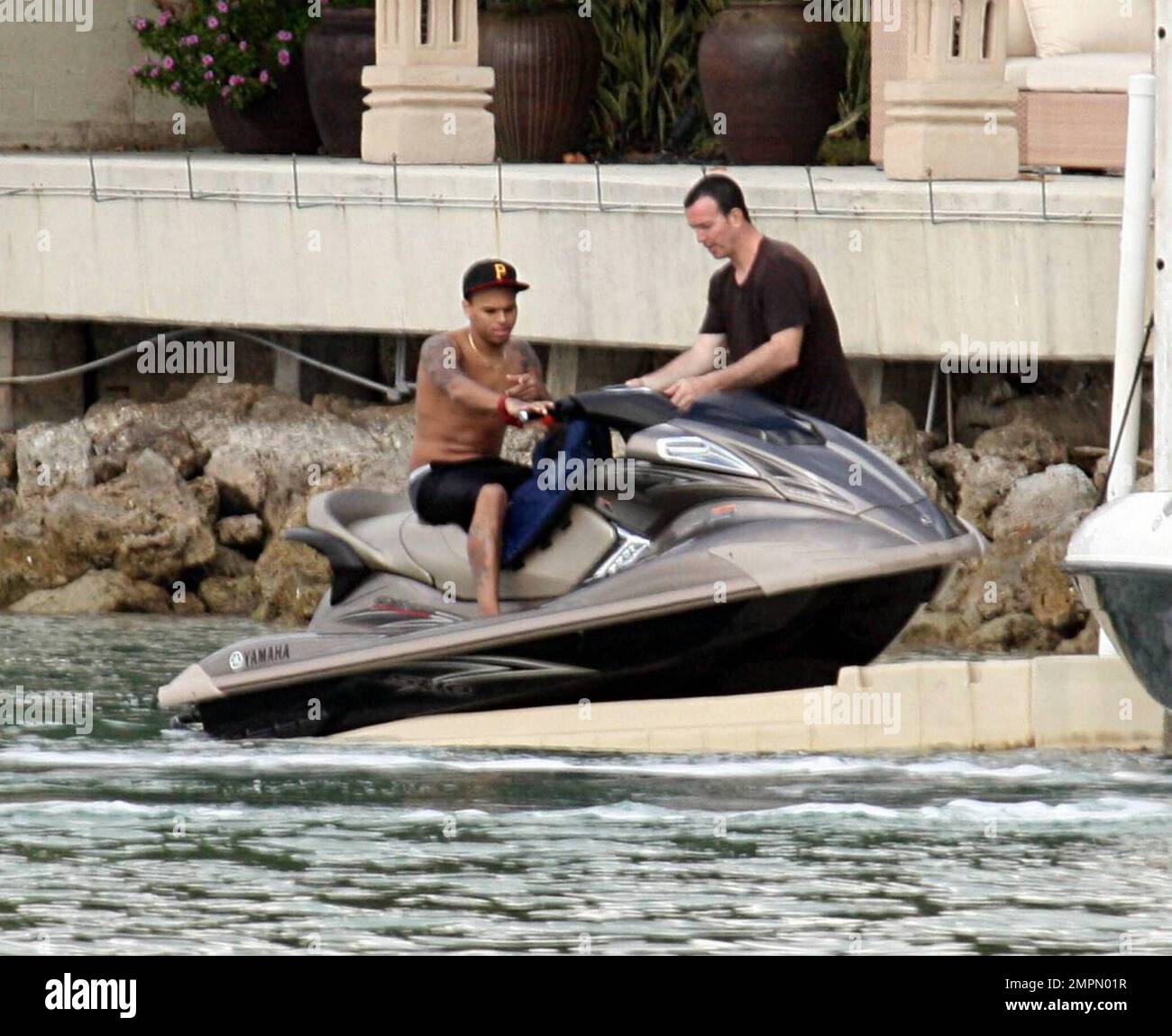 Chris Brown was all smiles and enjoying himself on a jetski after being reunited with girlfriend Rihanna at P Diddy's $50 million dollar Star Island mansion the previous night.  The reconciliation comes just two weeks after the domestic violence incident between Rihanna and boyfriend Chris that left Rihanna with cuts and bruises to her face and body.  The tattooed singer spent the day partying at P Diddy's with an entourage of girls and guys including one of Rihanna and Jay Z's bodyguards. Brown enjoyed himself on a jetski with a friend followed closely by security in a boat in the bay of Miam Stock Photo