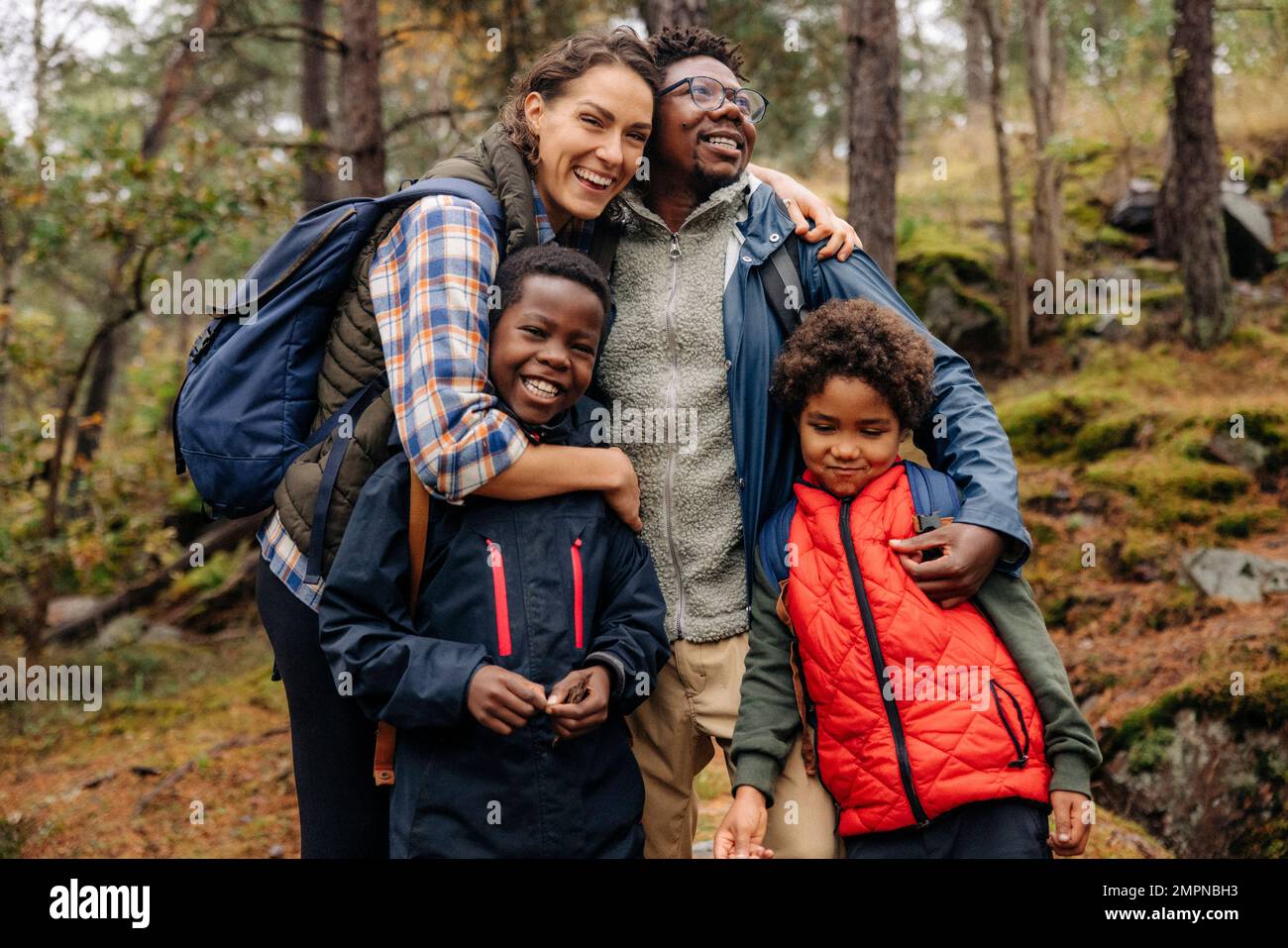 Happy family embracing each other while hiking in forest Stock Photo