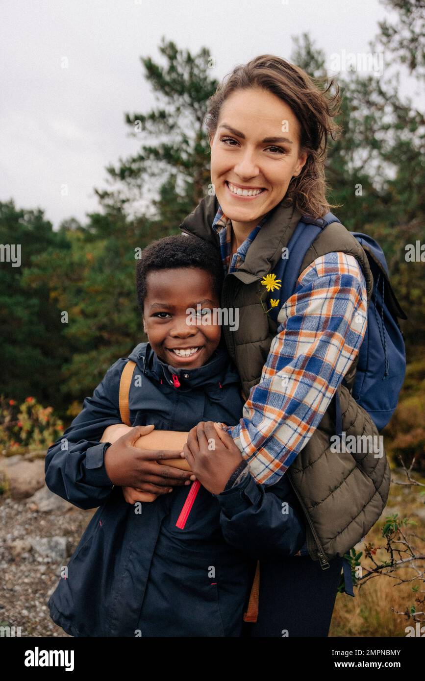 Portrait of happy mother embracing son while standing in forest Stock Photo