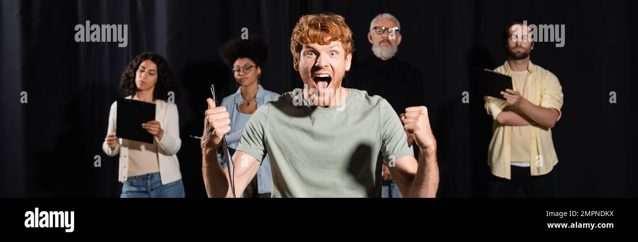 excited redhead man shouting and showing like gesture near producer and ...