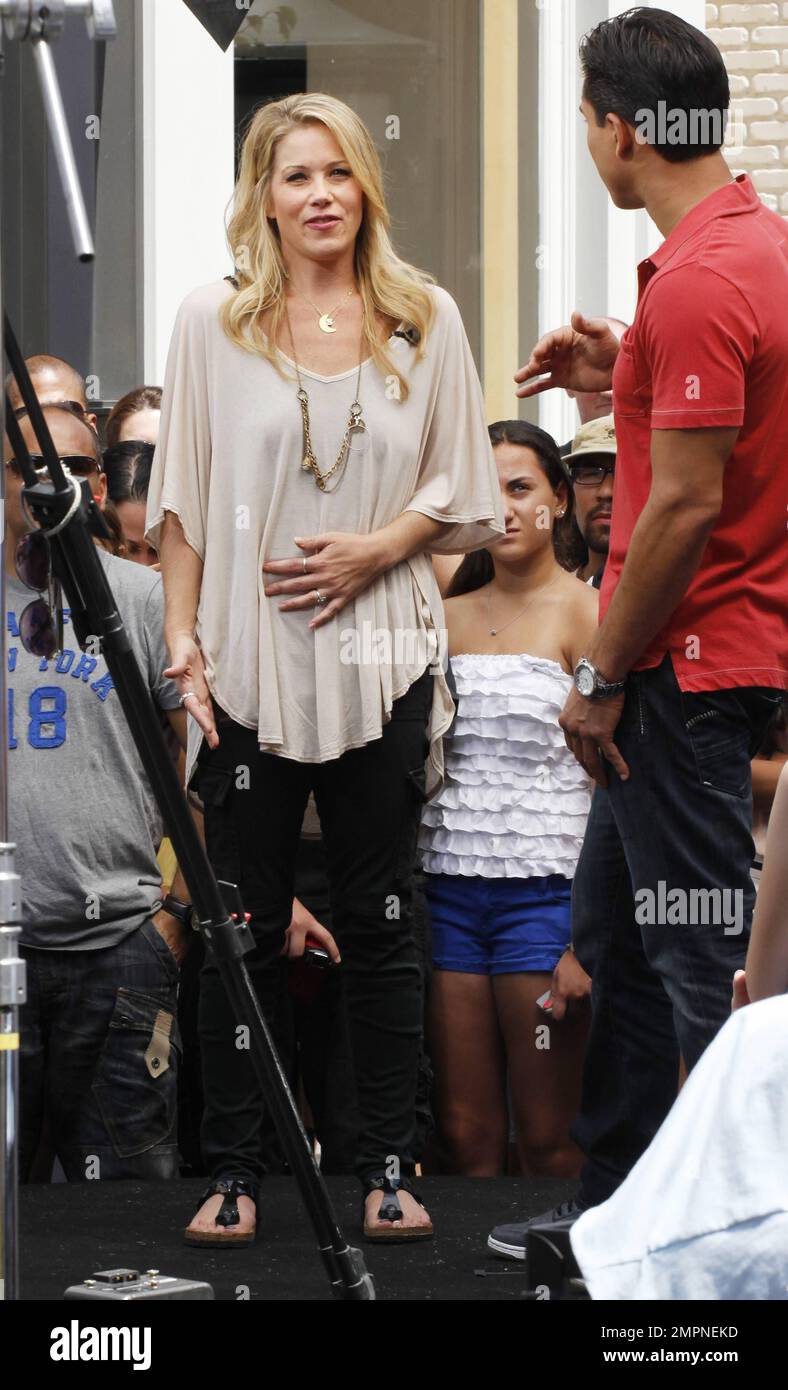 Wearing a loose tan top with black skinny jeans and sandals, Christina