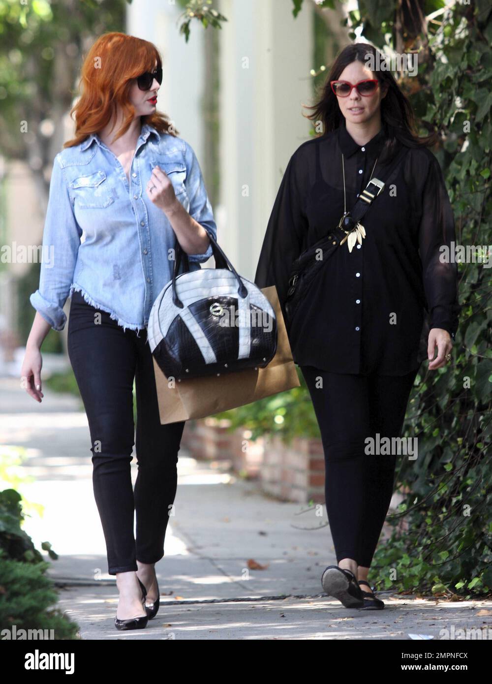 Looking glamorous in skinny jeans with black pumps and a denim shirt, "Mad  Men" star Christina Hendricks sports bright red lipstick as she gets in a  day of shopping with a friend.