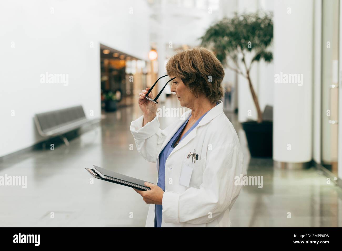 Side view of female doctor wearing eyeglasses while holding file at