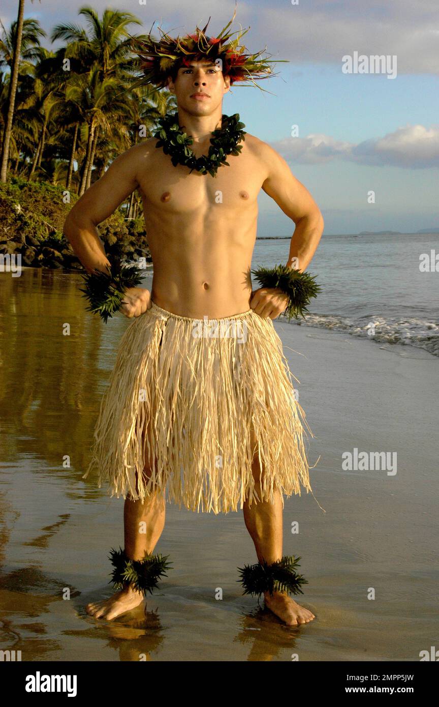 Male hula dancer poses with a power move at sunset by the beach. Stock Photo