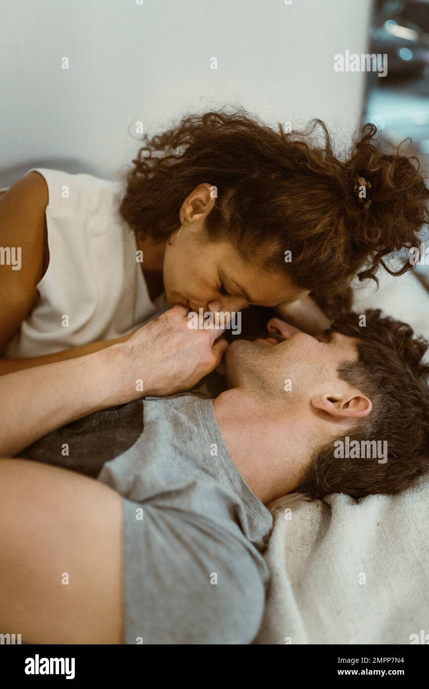 Girlfriend kissing boyfriend's hand lying on bed at home Stock Photo