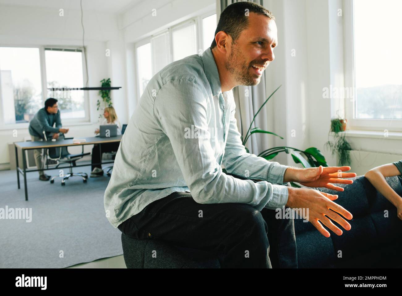Side view of smiling male businessman discussing at office Stock Photo