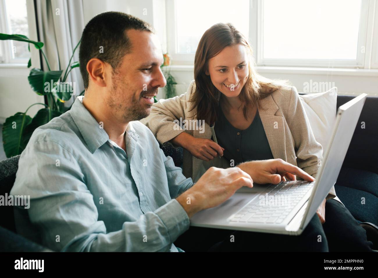 Happy business professionals working together on laptop while sitting at office Stock Photo