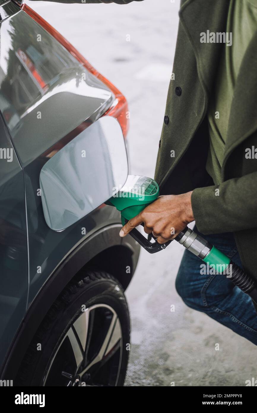Midsection of man refueling car at fuel station Stock Photo