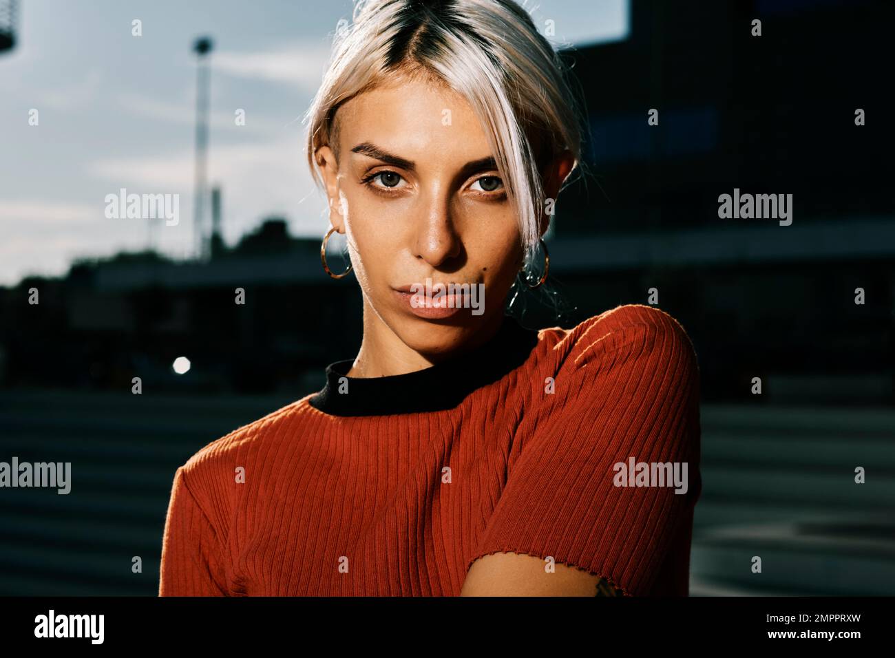 Woman looking at the camera while posing with her face lit outdoors. Stock Photo
