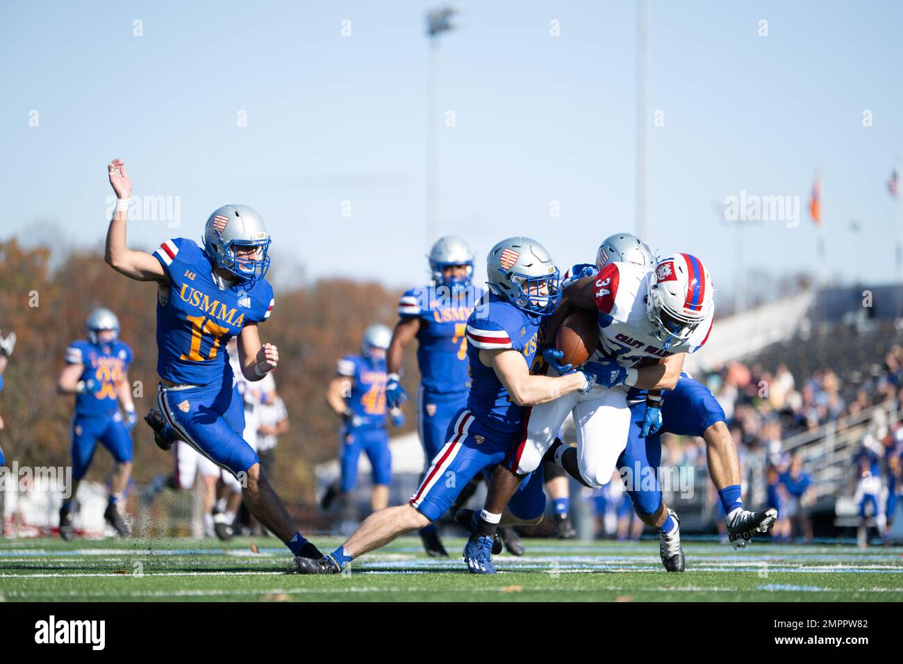 A Coast Guard Academy football player breaks the tackles of two