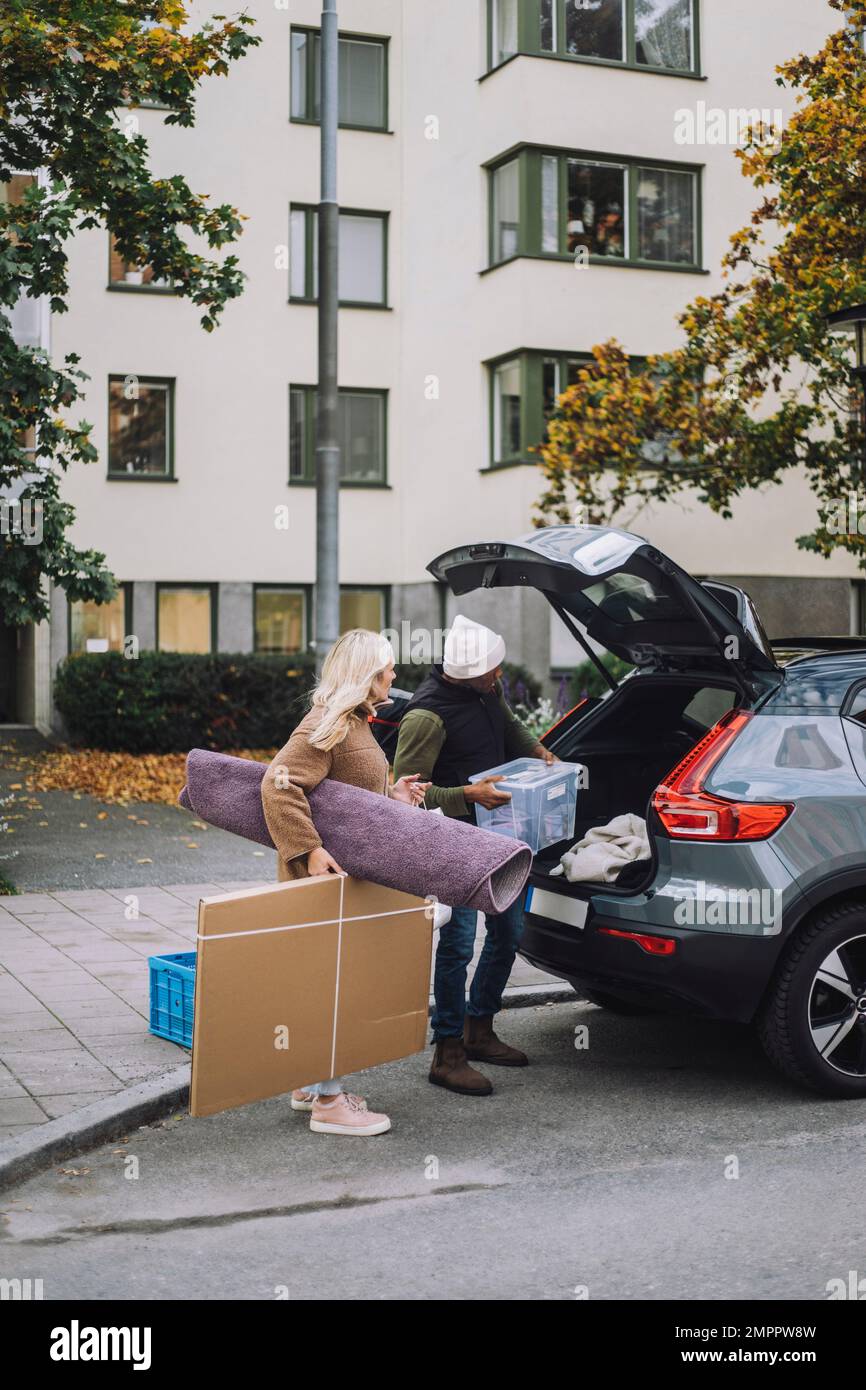 Mature couple loading luggage in car trunk during house relocation ...