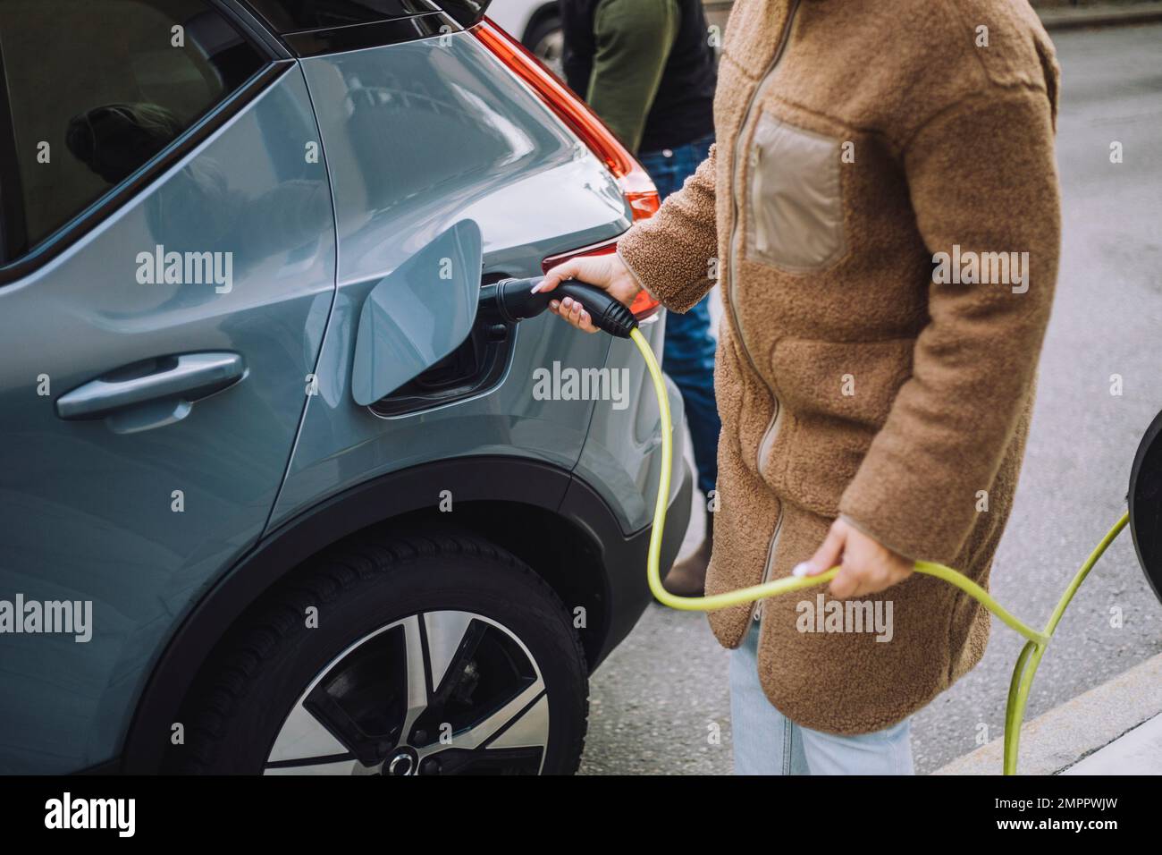 Midsection of woman charging electric car at station Stock Photo