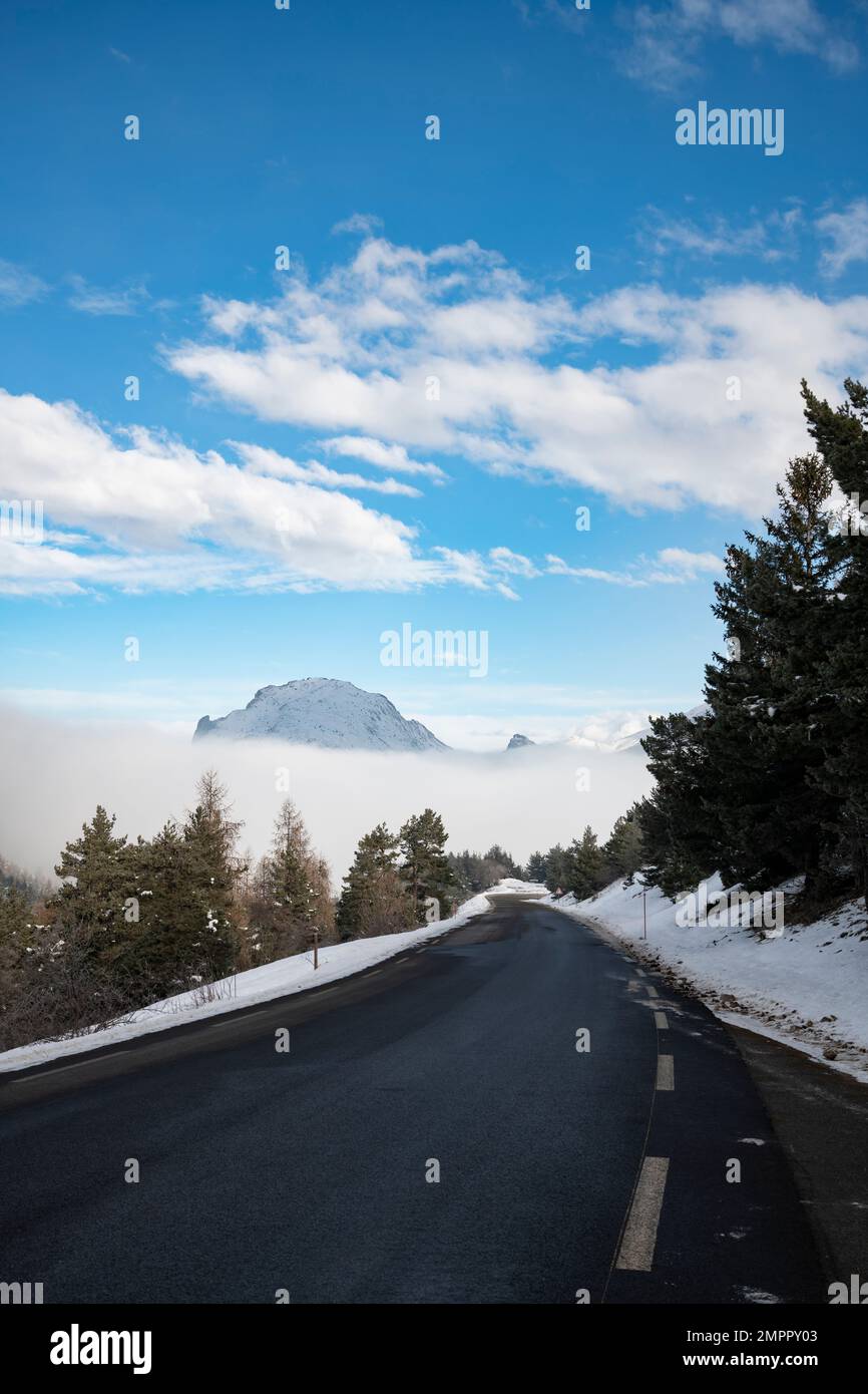 Road in winter with snow and fog in the valley, French Alps, France Stock Photo