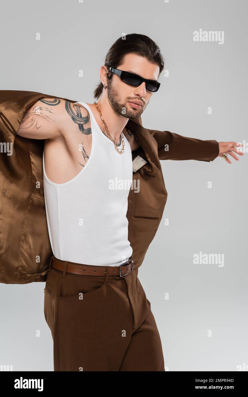 Fashionable tattooed man posing in jacket isolated on grey Stock Photo