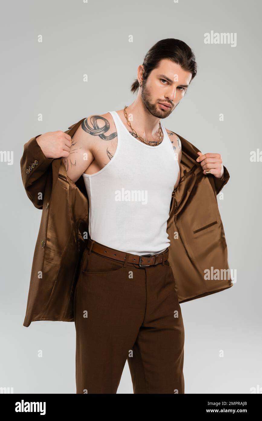 Stylish tattooed man in tank top wearing jacket isolated on grey Stock Photo
