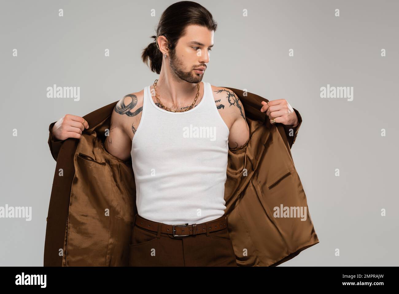 Long haired tattooed man wearing jacket isolated on grey Stock Photo