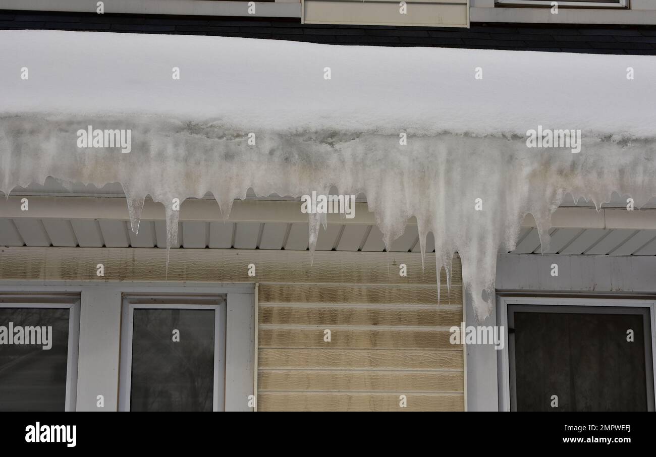 Melting snow on roof causing ice dam in gutter with icicles forming