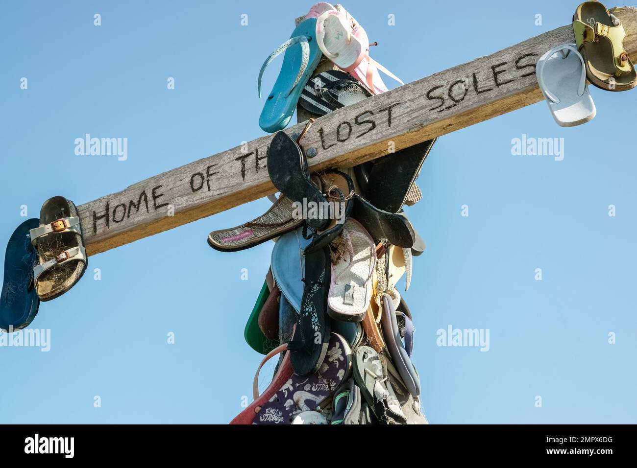 Castle Point New Zealand - October 5 2010: Collection lost footwear attached to cross on beach, Home of Lost Soles sign closeup. Stock Photo