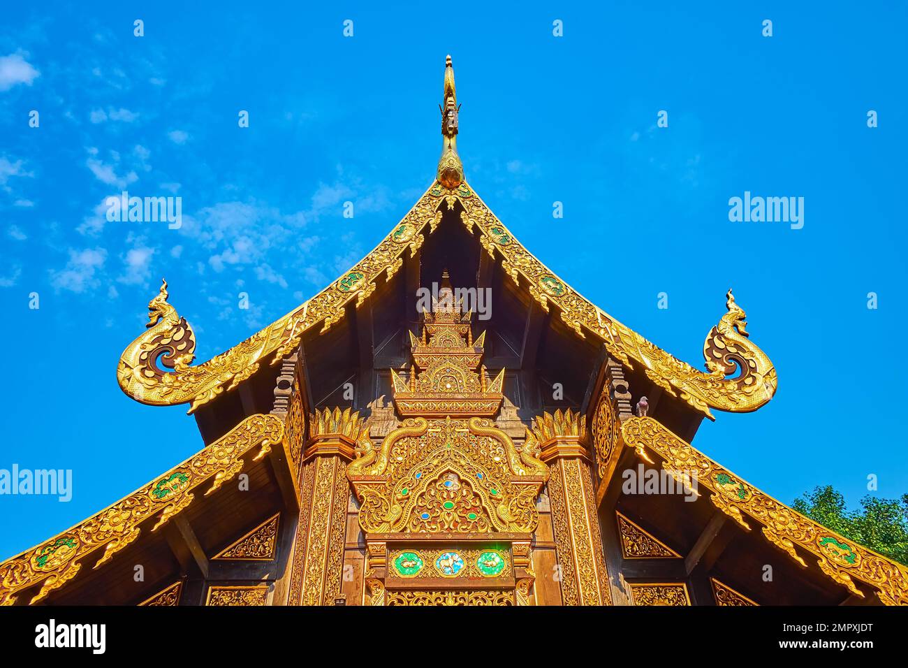 The carved, mirror mosaic and gilt decors of the multi-tired (pyathat) roof of Wat Inthakhin Sadue Muang, Chiang Mai, Thailand Stock Photo