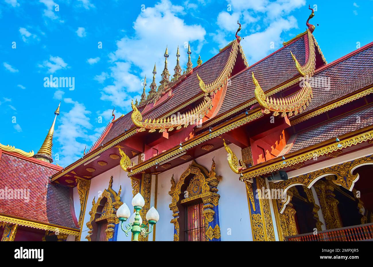 The carved gilt bargeboards, sculptured chofas and the hti umbrellas atop the red tile roof of the Viharn in Wat Saen Muang Ma temple, Chiang Mai, Tha Stock Photo