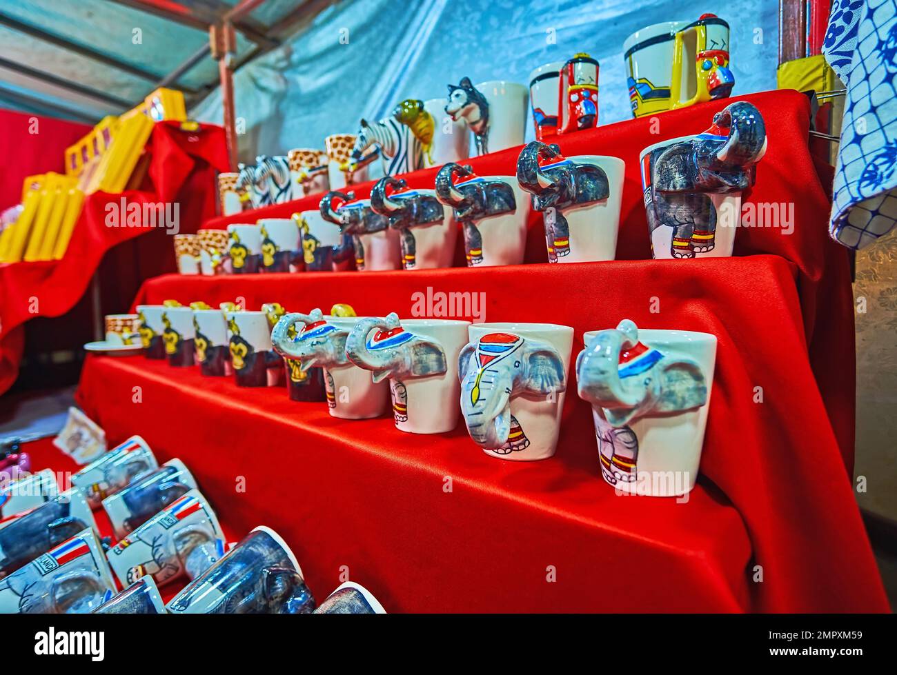 The line of porcelain mugs, decorated with elephants, monkeys, dogs and painted tuk tuks in stall of the Night Market in Chiang Mai, Thailand Stock Photo