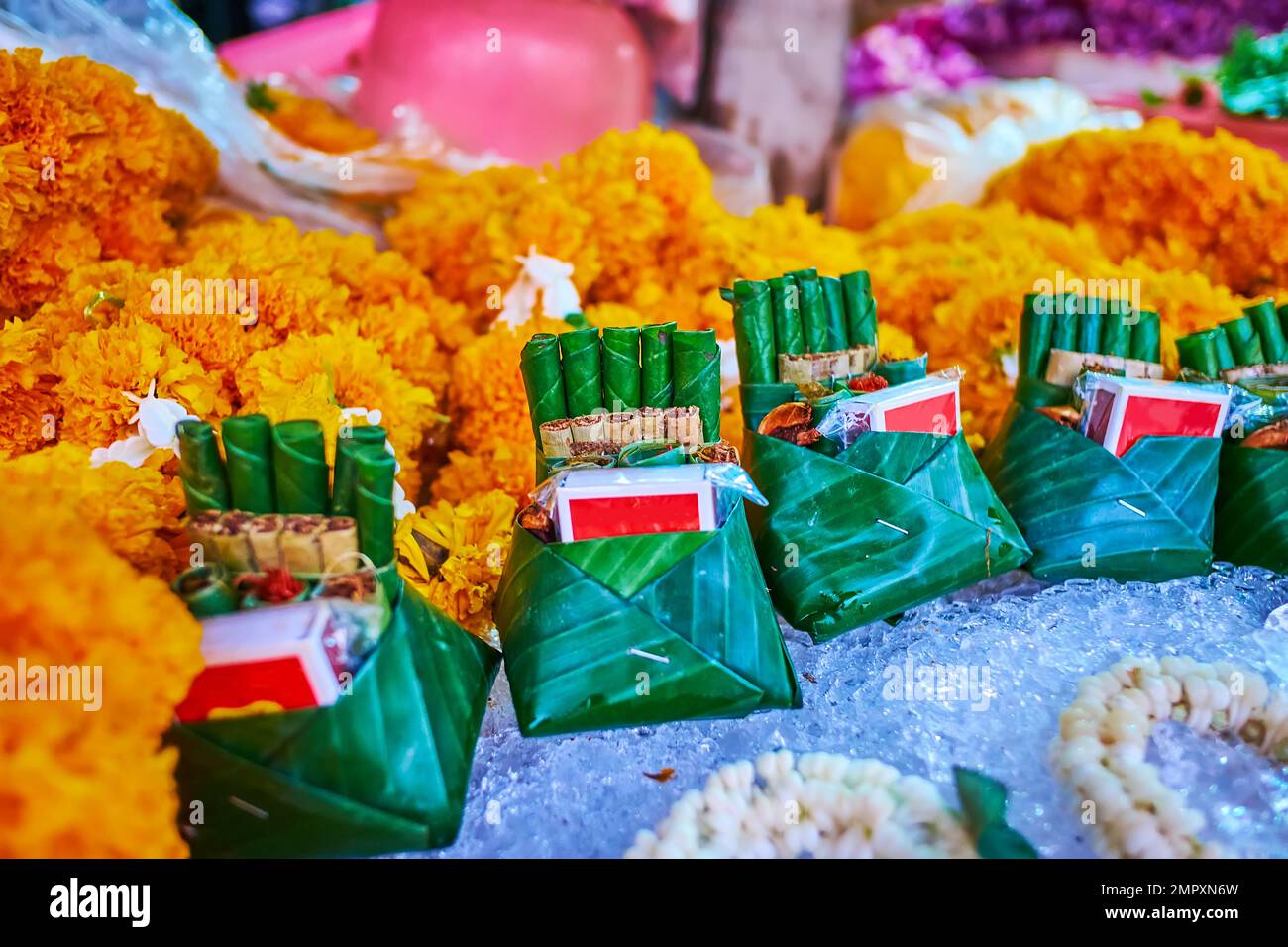 The counter of the stall with bright yellow marigolds and traditional Thai cigars, wrapped in banana leaves, Chiang Mai, Thailand Stock Photo