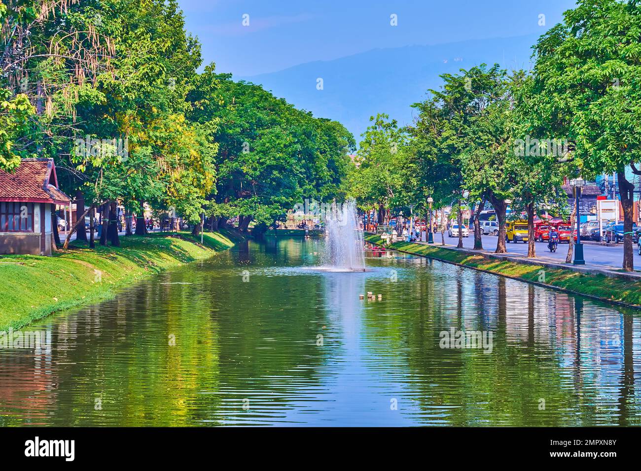 The Old City Moat with fountains and lush green park, reflected on water surface, Chiang Mai, Thailand Stock Photo