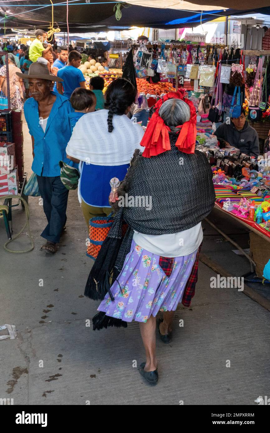 An indigenous Zapotec woman in traditional dress walks though the market in Ocotlan de Morelos