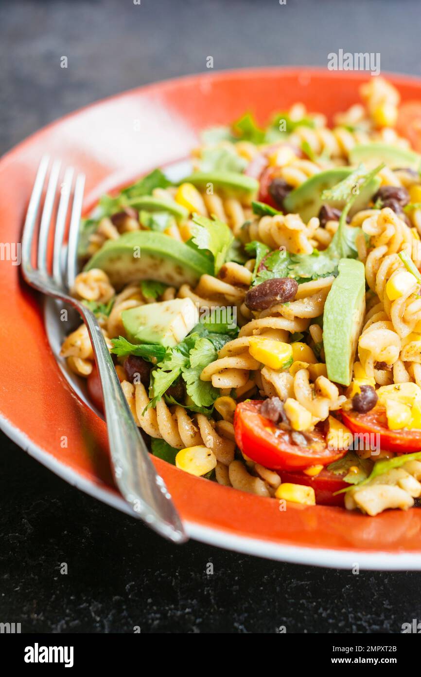 Home made vegan Mexican pasta salad with avocado, beans and corn. Stock Photo