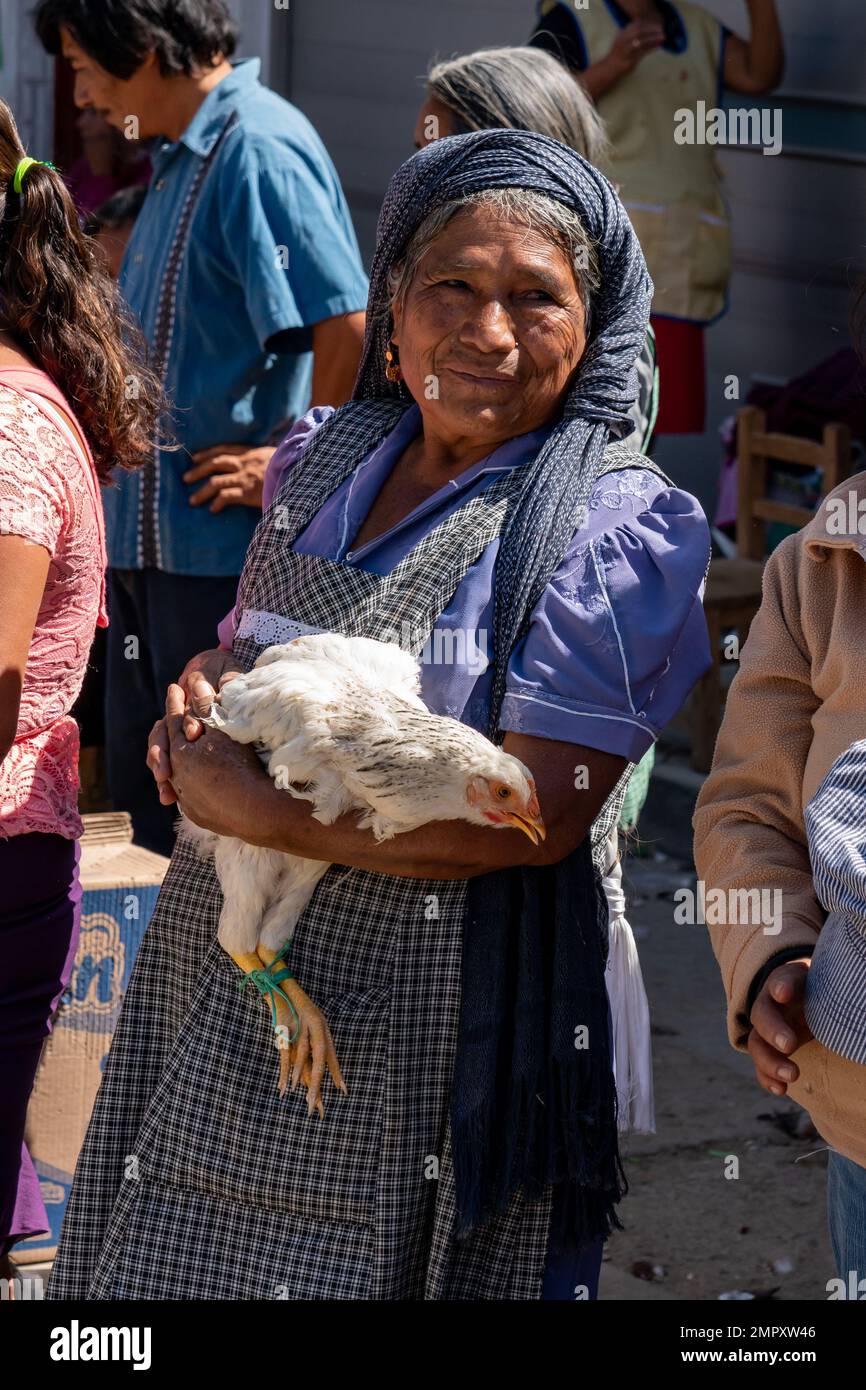An indigenous Zapotec woman in traditional dress selling a chicken in the market in Ocotlan de