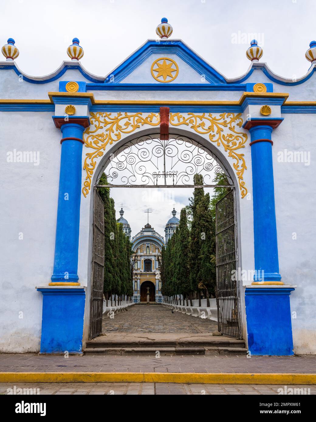 A colorful painted gateway framing the Church of Santo Domingo de Guzman in Ocotlan de Morelos, Oaxaca, Mexico. Stock Photo