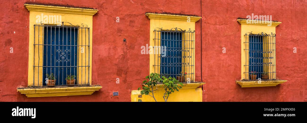 Windows with cast iron grates in a colorfully-painted residence in the Xochimilco district of historic city of Oaxaca, Mexico. Stock Photo