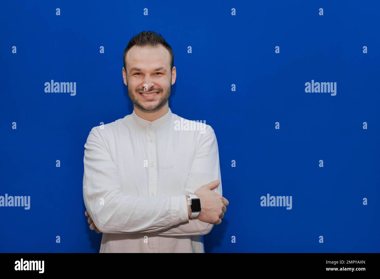 Positive and cheerful guy Caucasian appearance stylish businessman in a white shirt on a blue background. Stock Photo