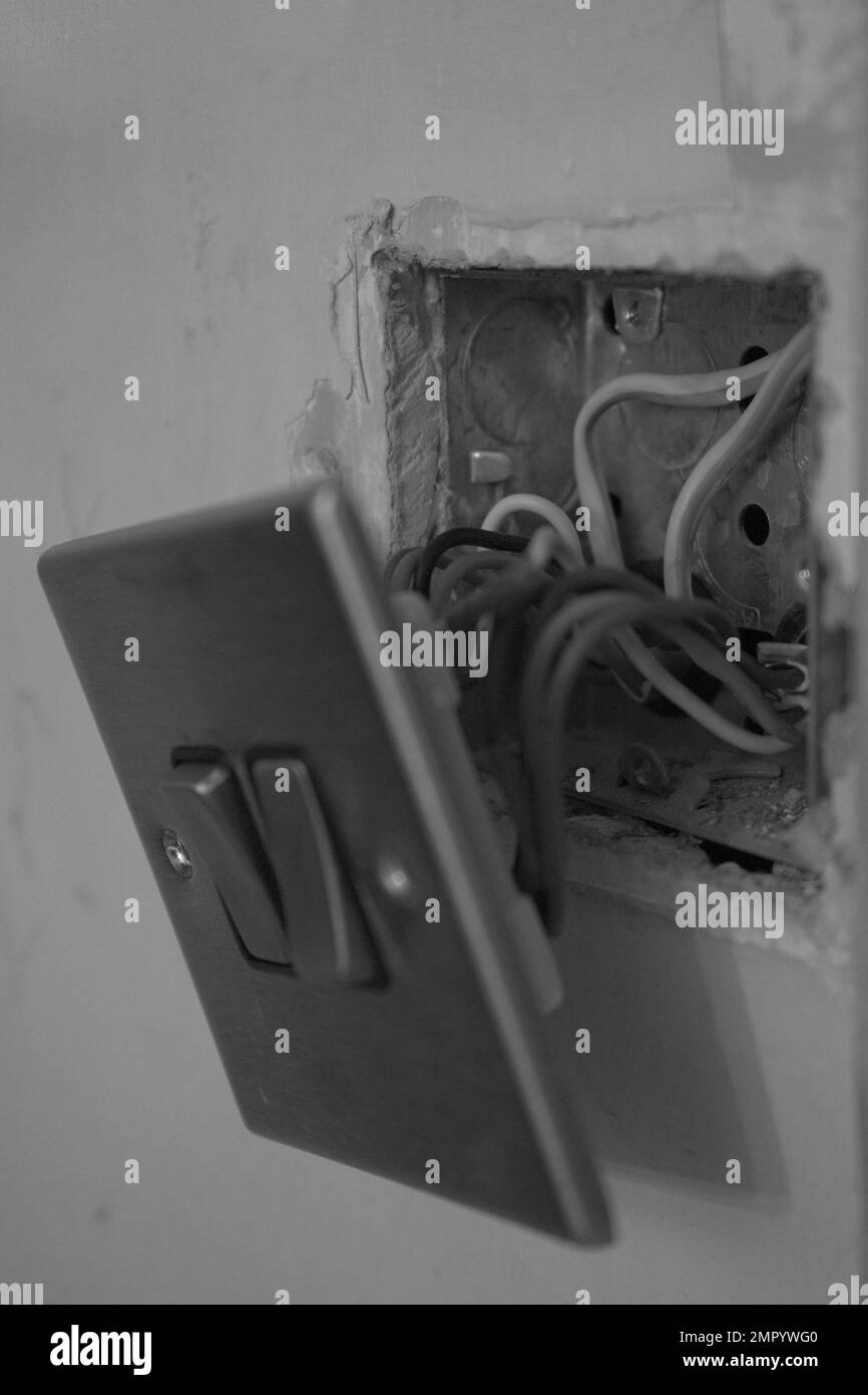 Black and white photo of metallic silver light switch, housing and electrical wiring Stock Photo