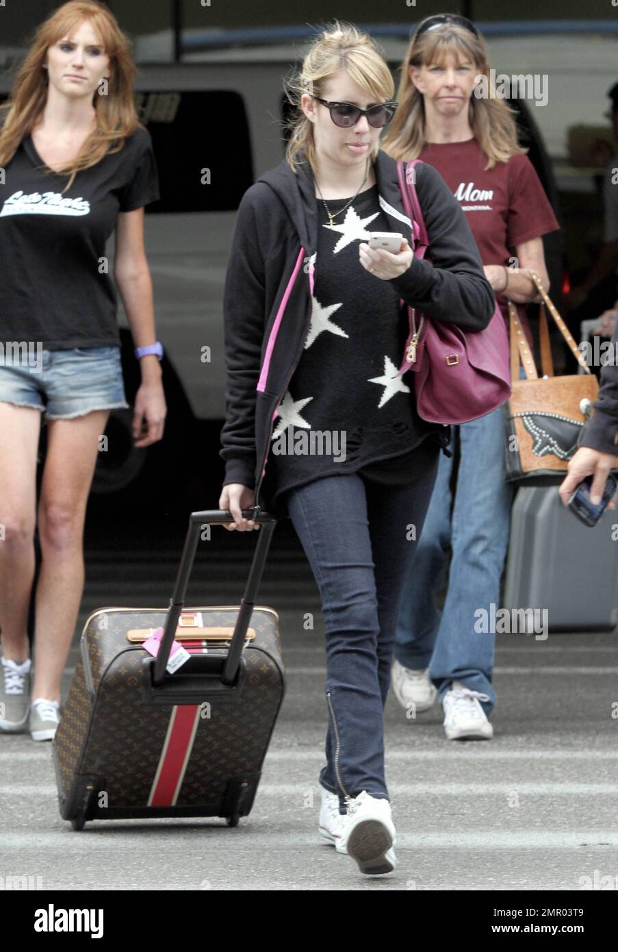 Actress Emma Roberts wears an all-black outfit consisting of a  star-patterned sweater, hoodie and jeans paired with white sneakers as she  arrives at LAX after a flight from Atlanta, GA. Roberts, who
