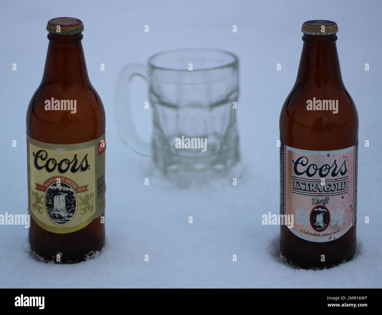 Two old Coors beer bottles chilled in the snow with a beer mug. Stock Photo
