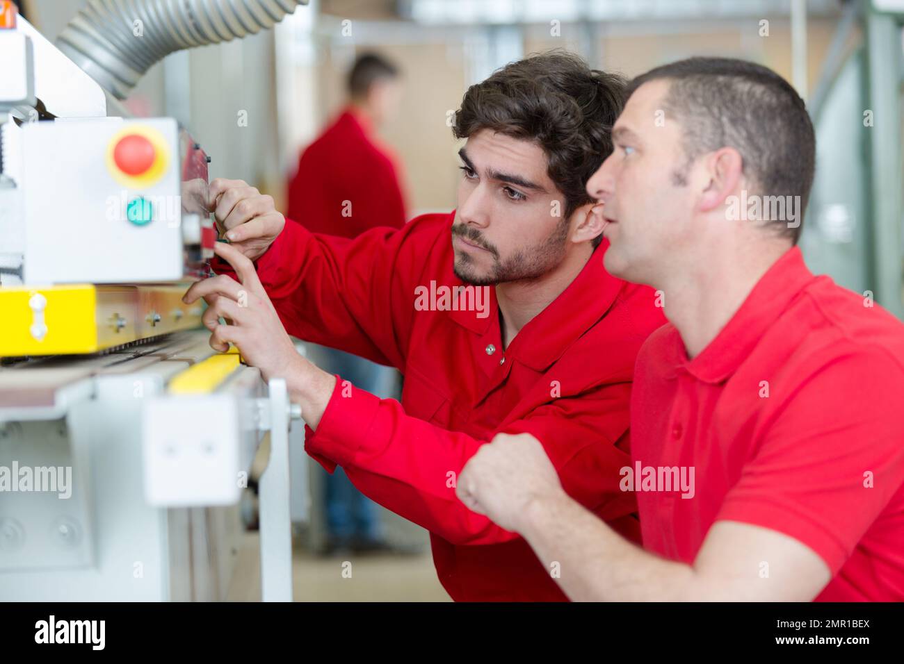 engineer and apprentice using computerized cutting machine Stock Photo ...