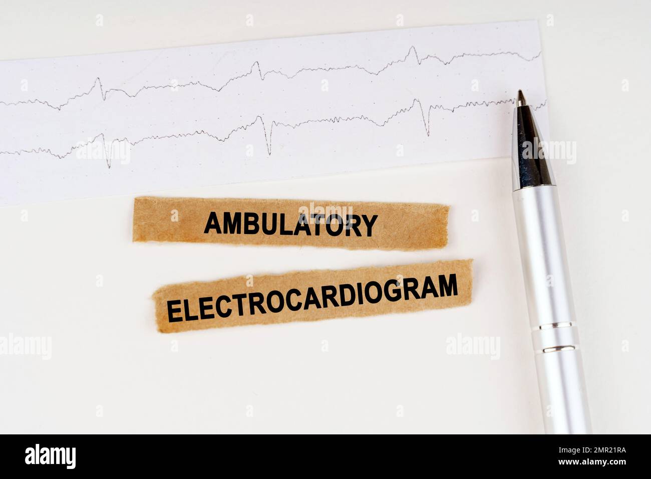 Medical concept. On the cardiogram lies a pen and torn paper with the text - Ambulatory Electrocardiogram Stock Photo