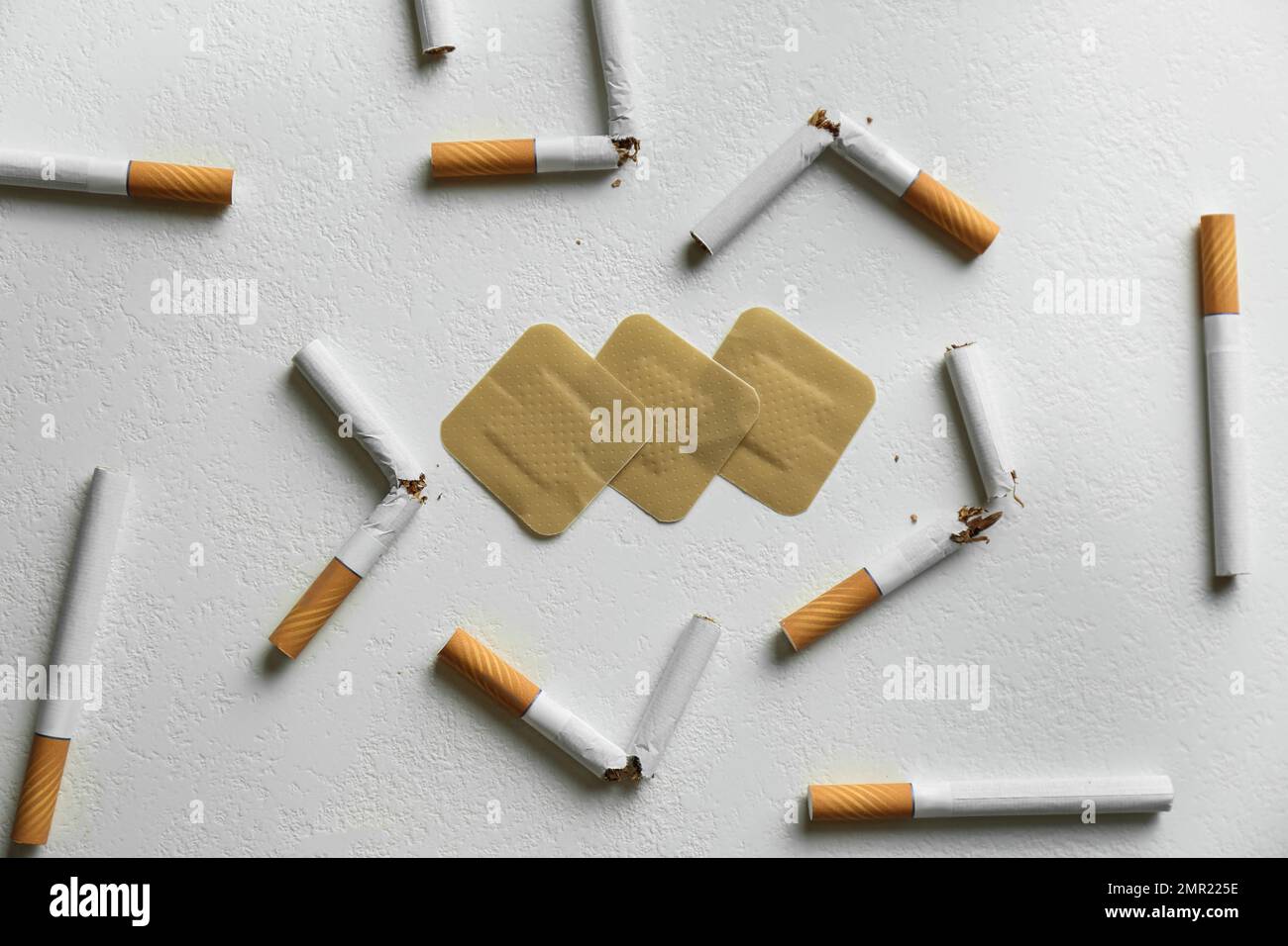 Nicotine patches and broken cigarettes on white background, flat lay
