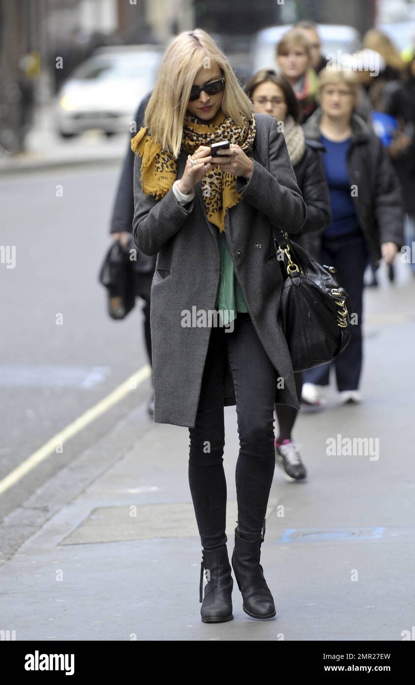 After returning from a holiday in Sri Lanka, Fearne Cotton checks her new iPhone as she walks in the West End. Fearne wore a grey coat and patterned yellow scarf paired with tight black jeans and boots as she strolled. London, UK. 9th January 2012. Stock Photo