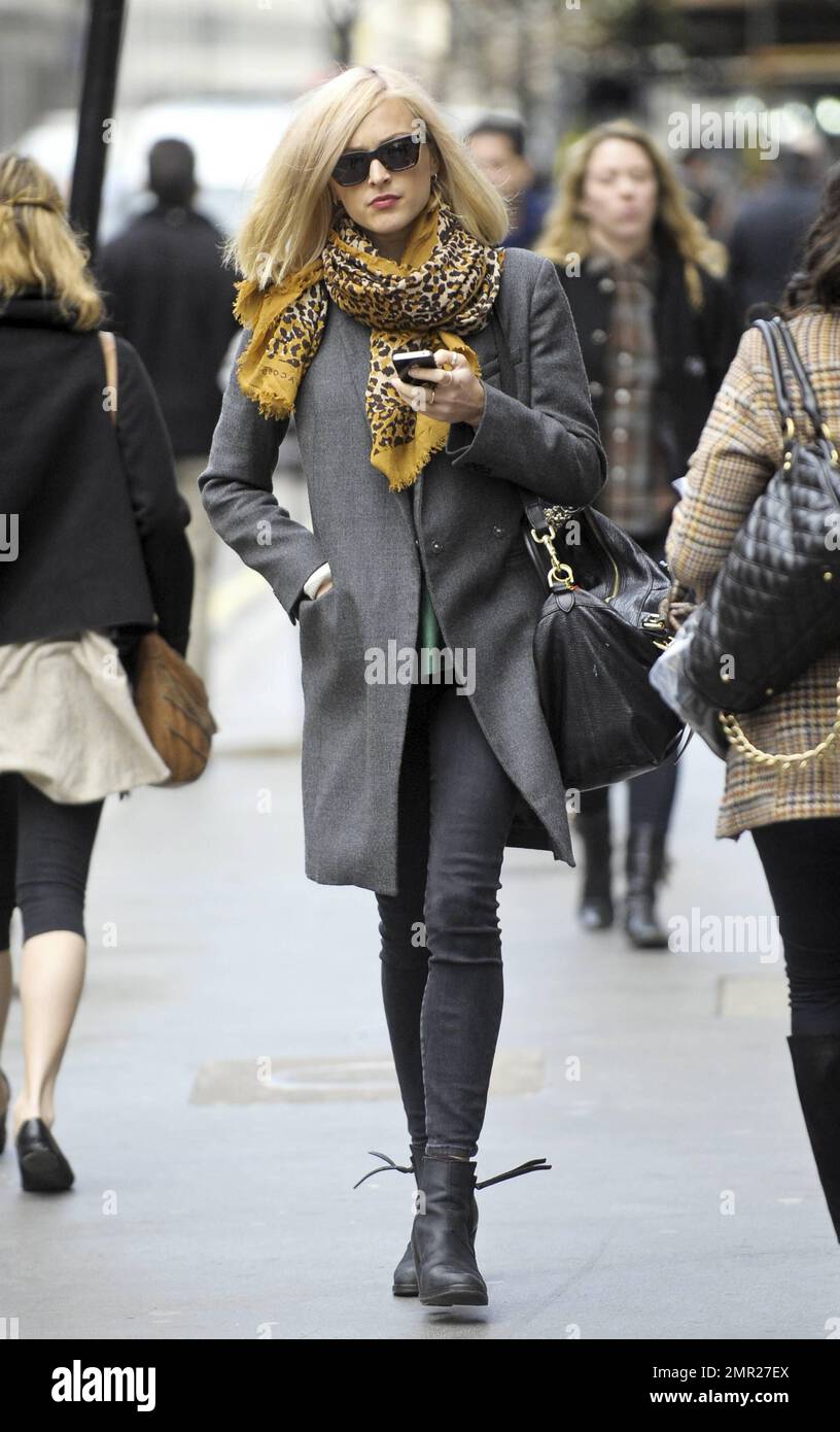 After returning from a holiday in Sri Lanka, Fearne Cotton checks her new iPhone as she walks in the West End. Fearne wore a grey coat and patterned yellow scarf paired with tight black jeans and boots as she strolled. London, UK. 9th January 2012. Stock Photo