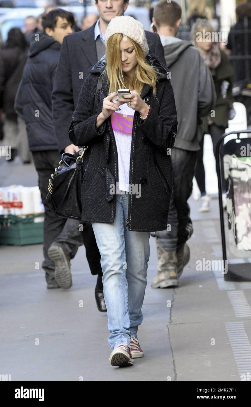 Wearing a white wooly cap, black coat, jeans and a t shirt with pink  Converse All-Star sneakers, Fearne Cotton looks focused on her cellphone as  she leaves the BBC. London, UK. 2/24/11