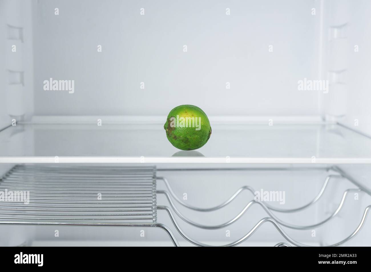 Old lime on empty shelf in refrigerator Stock Photo