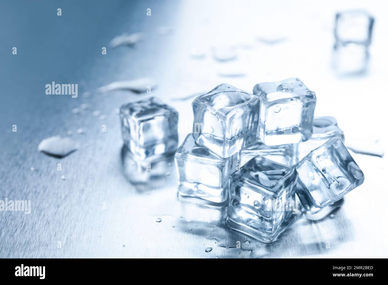 Crystal clear ice cubes with water drops on metal surface Stock Photo